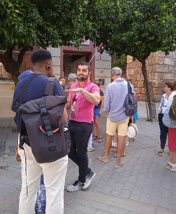 Tour guide with group using selfie stick on a city street.
