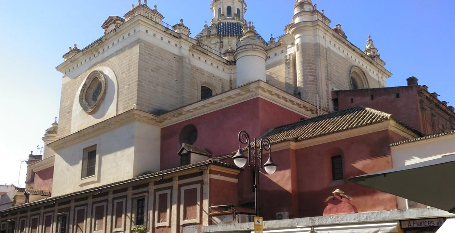 Historic church with red and white facade, domes, and ornate details under blue sky.