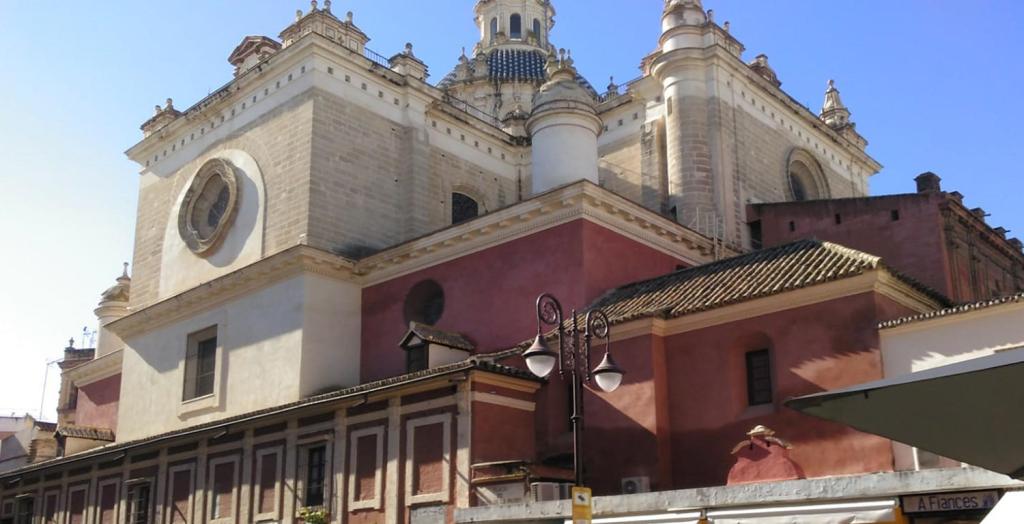 Historic church with red and white facade, domes, and ornate details under blue sky.