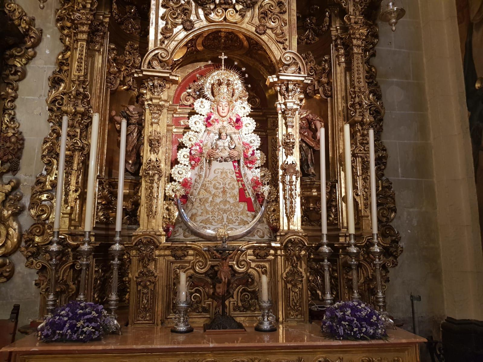 Ornate religious statue with floral decorations in a gilded altar.