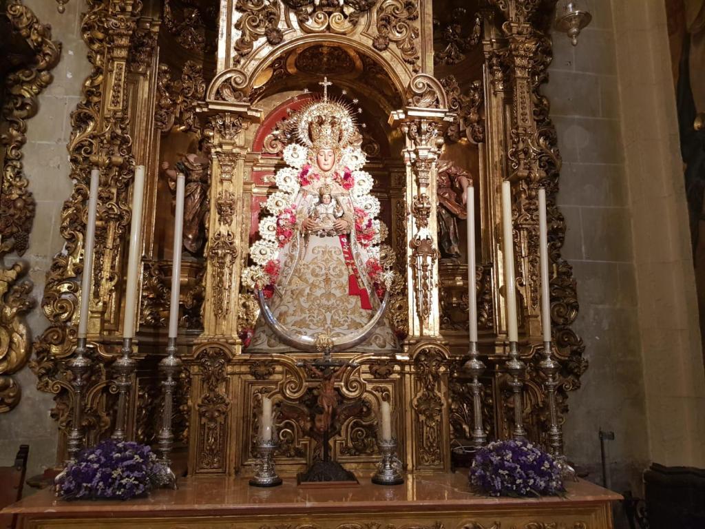 Ornate religious statue with floral decorations in a gilded altar.