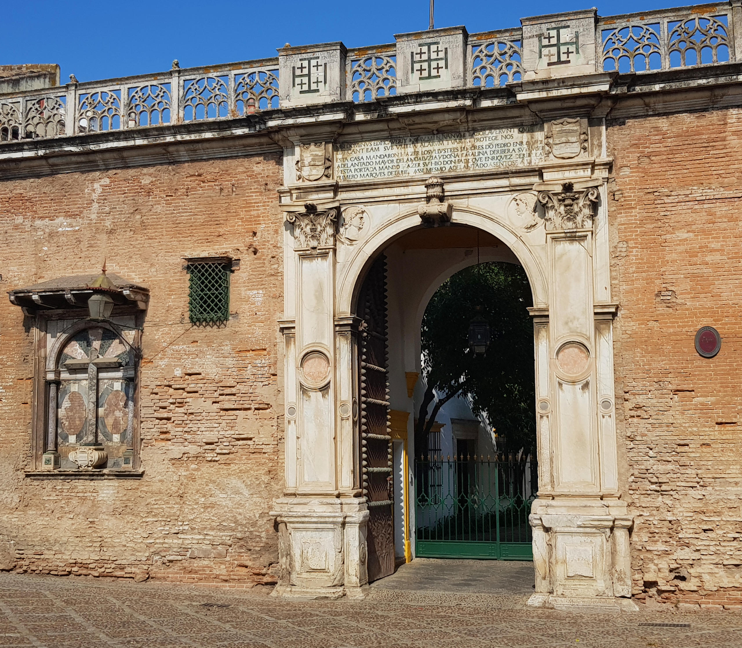 Ornate stone archway in old brick wall on sunny day.