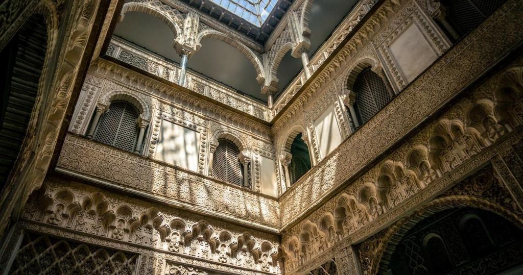 Intricate arches and detailed carvings in a sunlit courtyard of a historic building.